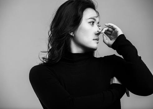 Artistic black and white portrait of a woman in a thoughtful pose, conveying emotion and depth.